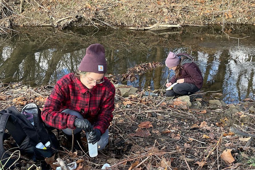 Eliza Siefert (from left), water resources technician at the West Virginia Water Research Institute, and Rachel Spirnak, water resources specialist at WVWRI, collect samples in Chartiers Creek on a sampling day.