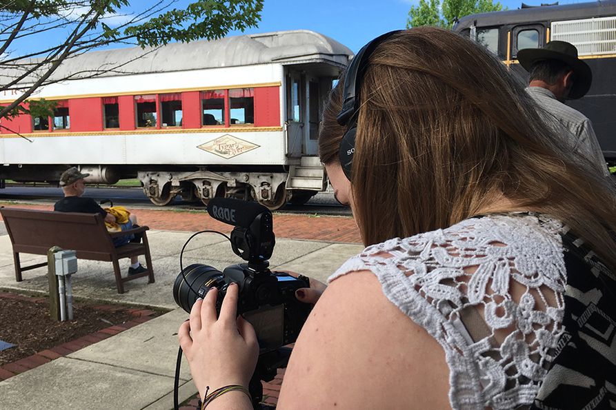A WVU Reed College of Media student takes photos at a train station during the 2018 project.